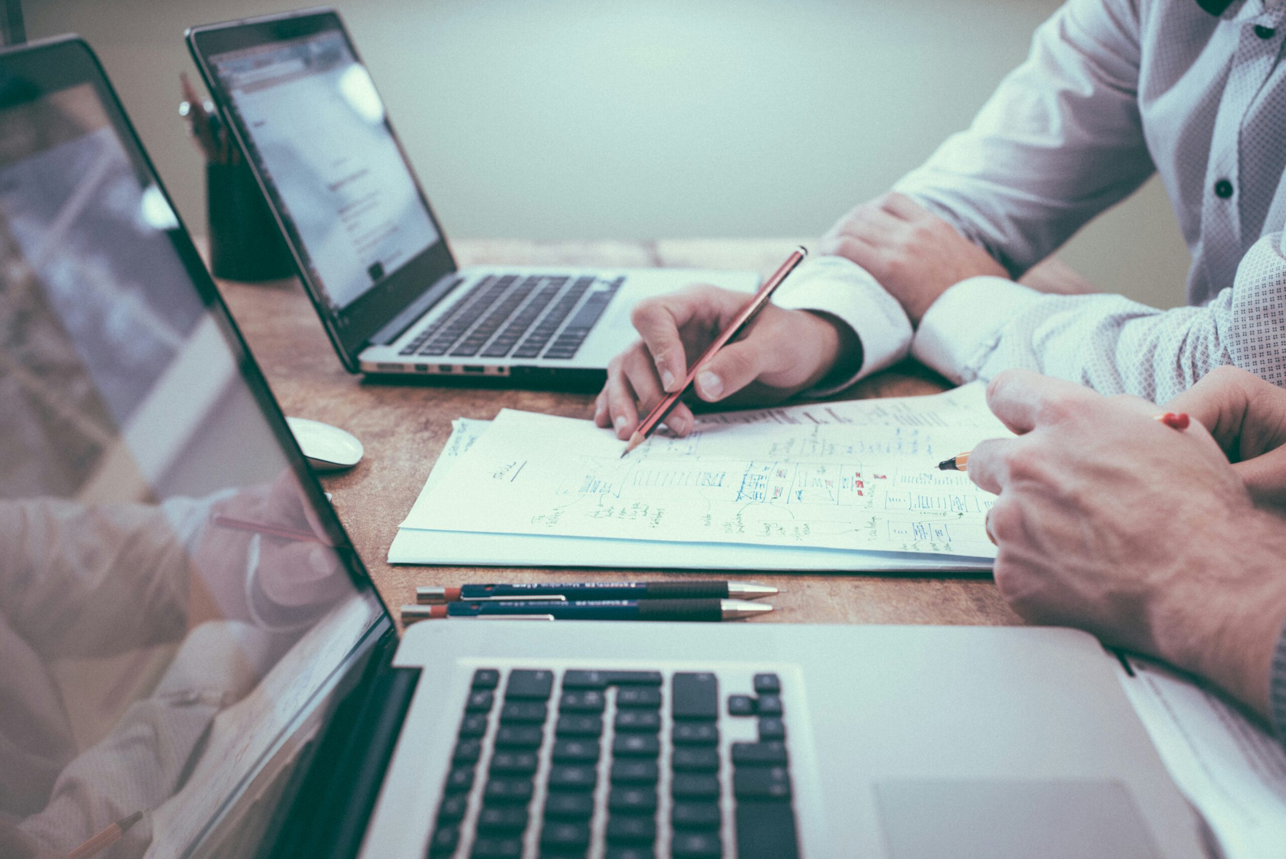 Colleagues collaborate over handwritten notes and laptops at a meeting table