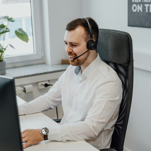 Man wearing a headset works at a computer in an office
