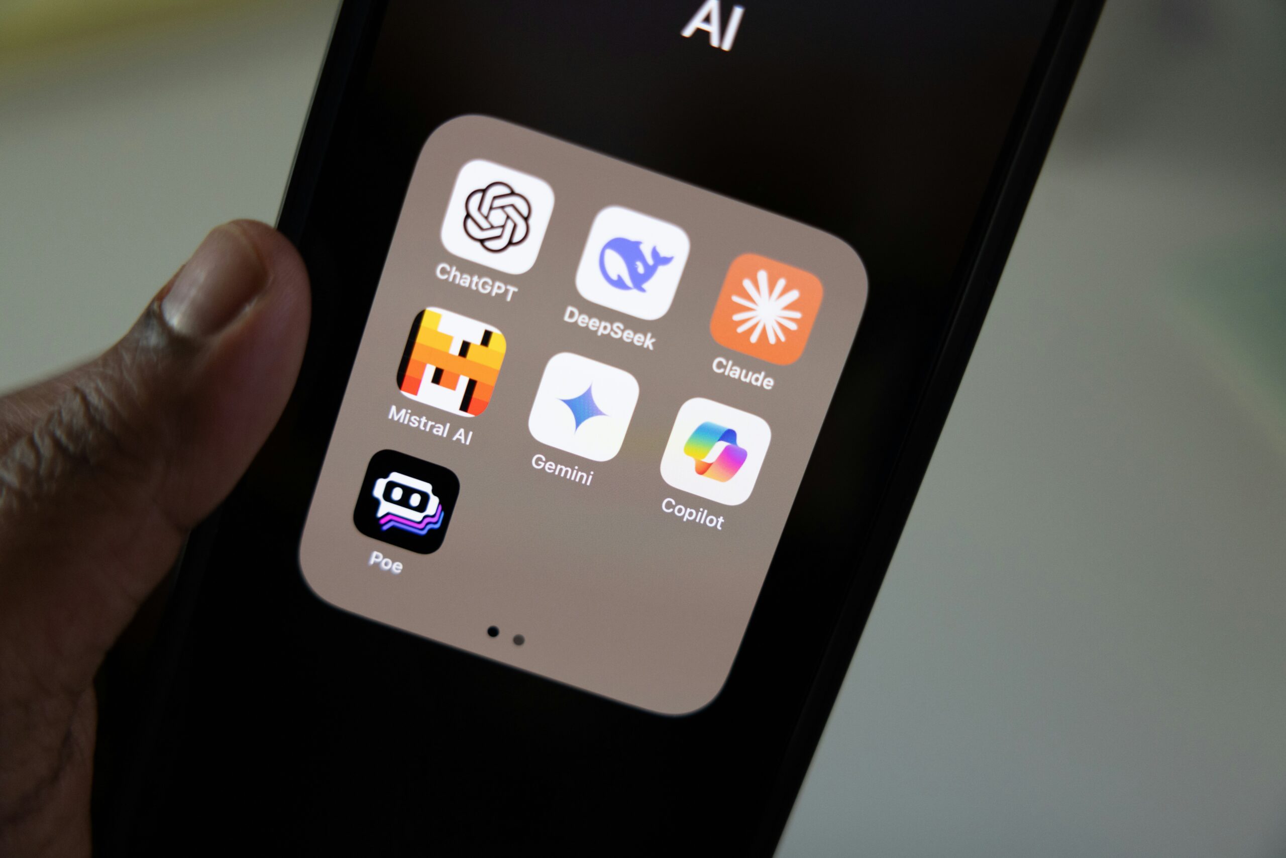 Smartphone screen displaying AI app icons for ChatGPT, DeepSeek, Claude, Mistral AI, Gemini, Copilot and Poe