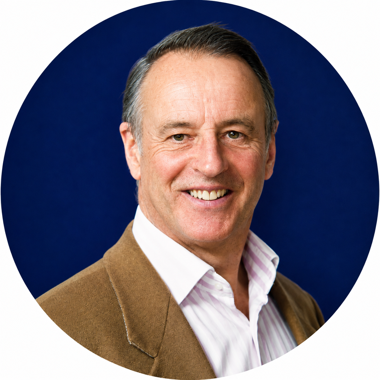 Smiling middle-aged man in a brown jacket and striped shirt against a dark blue background