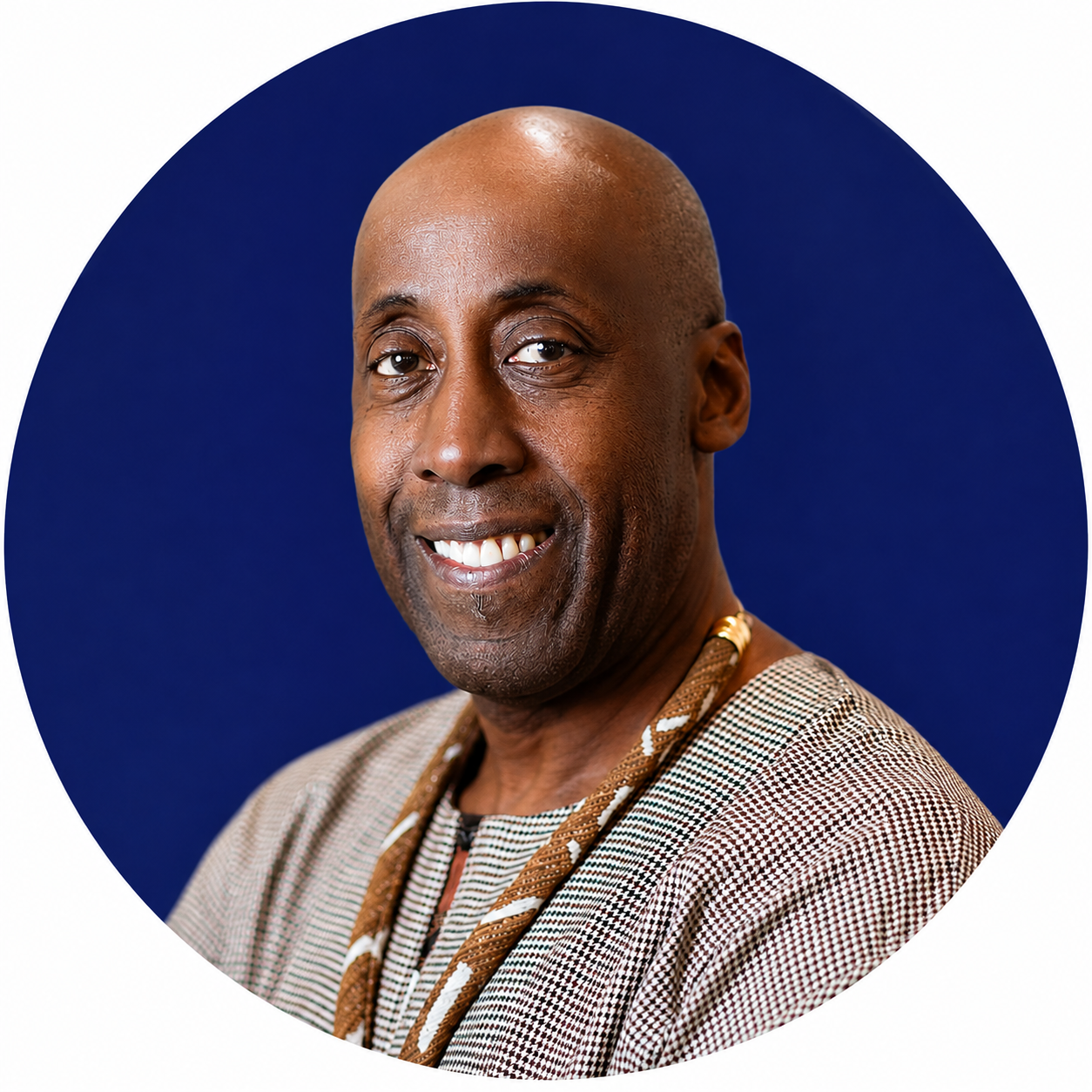 Smiling bald man wearing a patterned jacket and necklace against a dark blue circular background